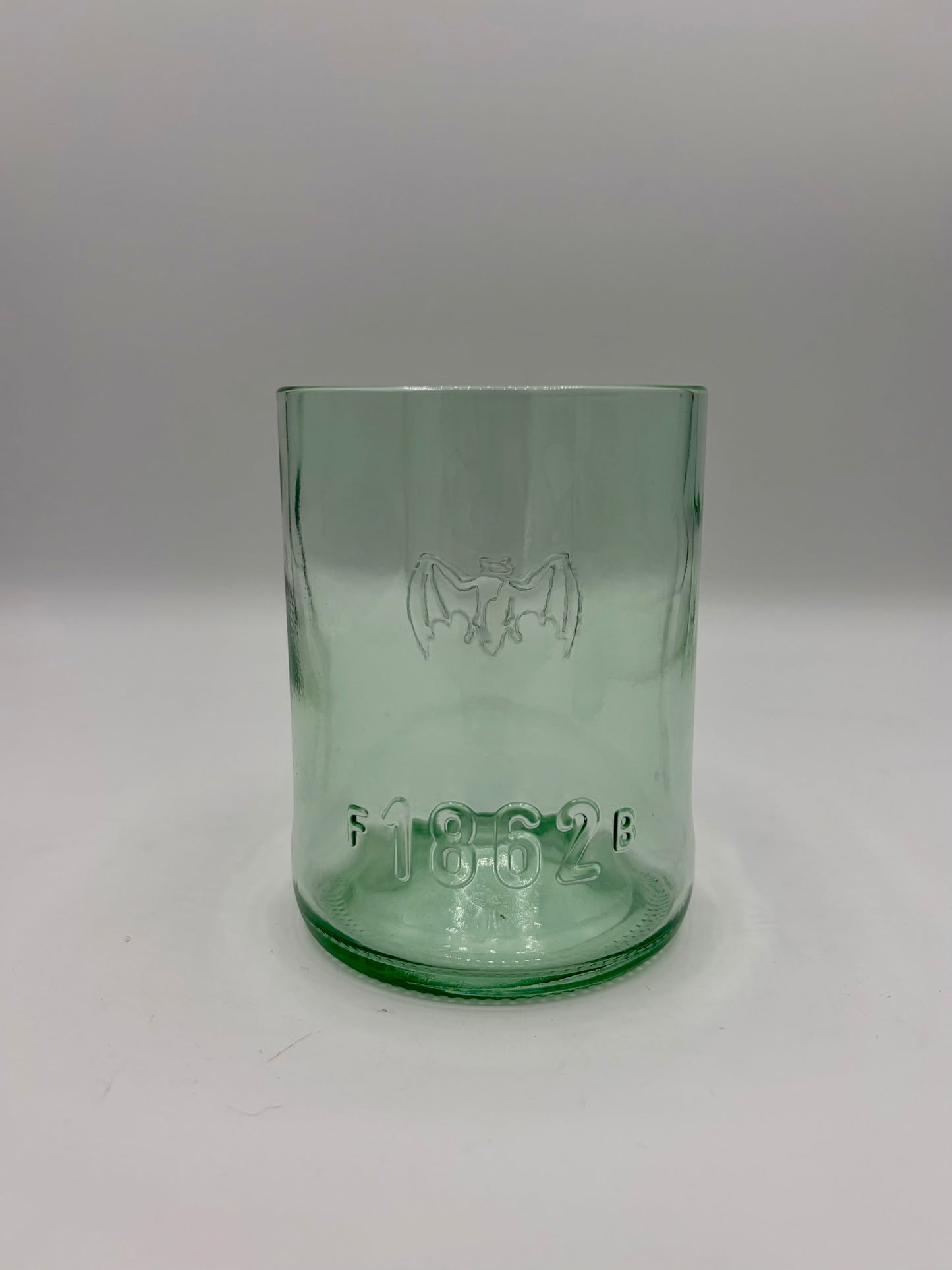 Broken Arrow Glass Recycling upcycled Bacardi bottle tumbler in sea glass green with embossed bat and 1862 logo.
