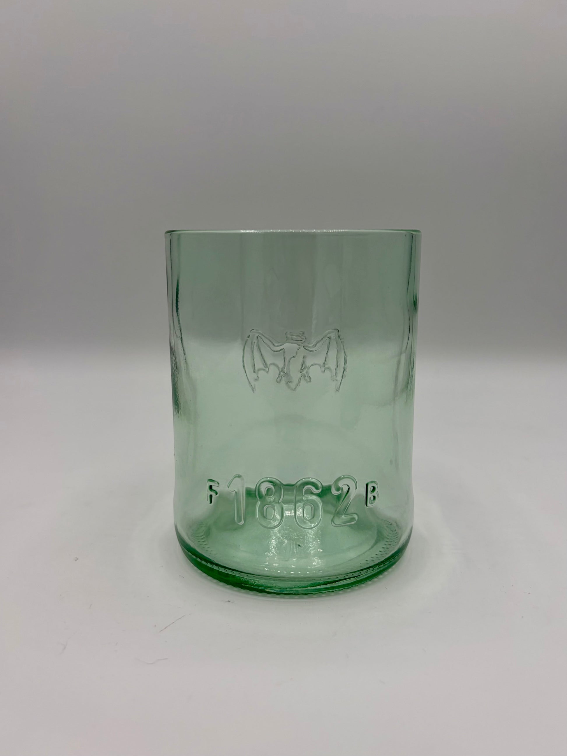 Broken Arrow Glass Recycling upcycled Bacardi bottle tumbler in sea glass green with embossed bat and 1862 logo.
