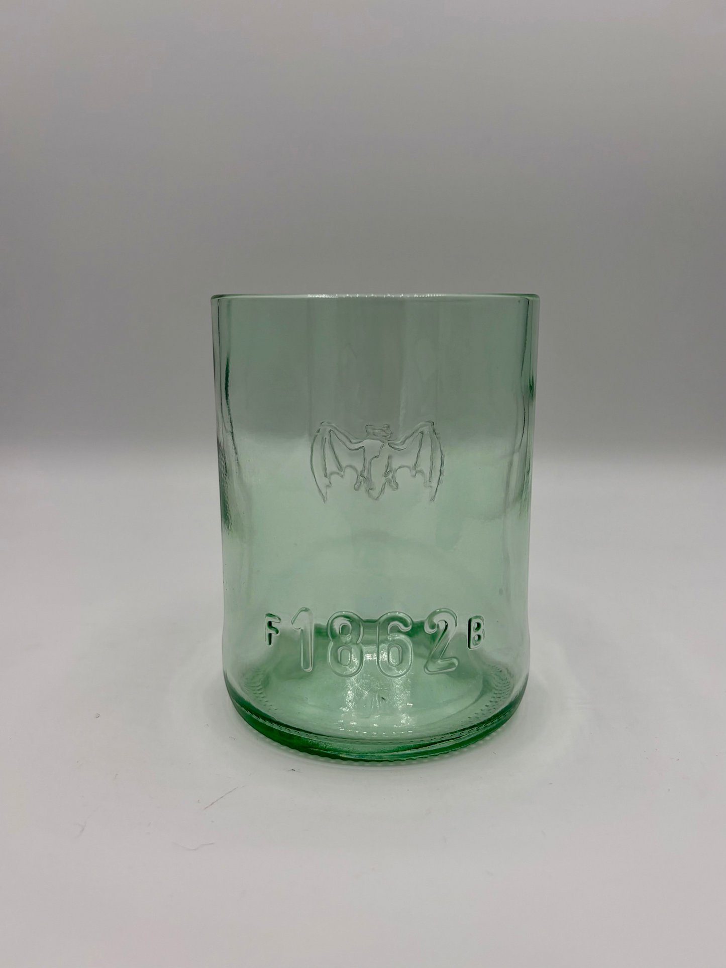 Broken Arrow Glass Recycling upcycled Bacardi bottle tumbler in sea glass green with embossed bat and 1862 logo.