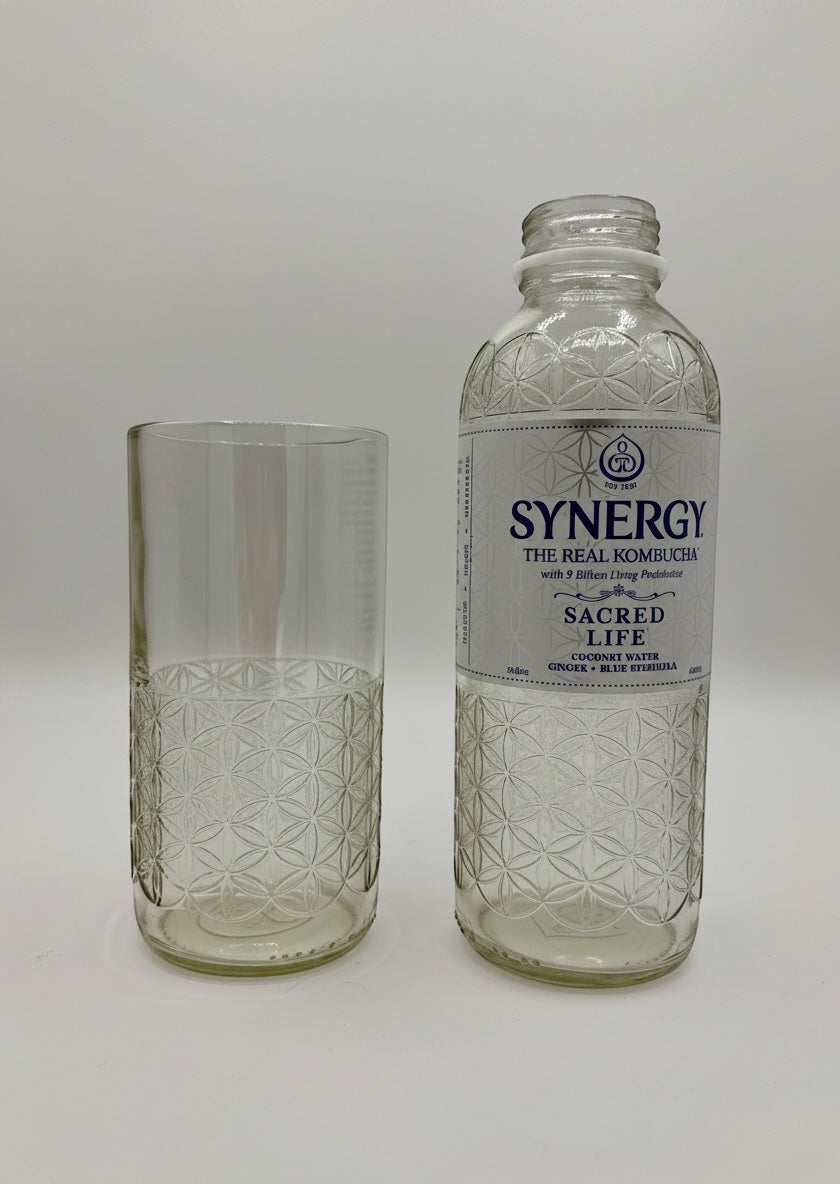Broken Arrow Glass Recycling upcycled tumbler next to a Synergy kombucha bottle with embossed flower of life pattern