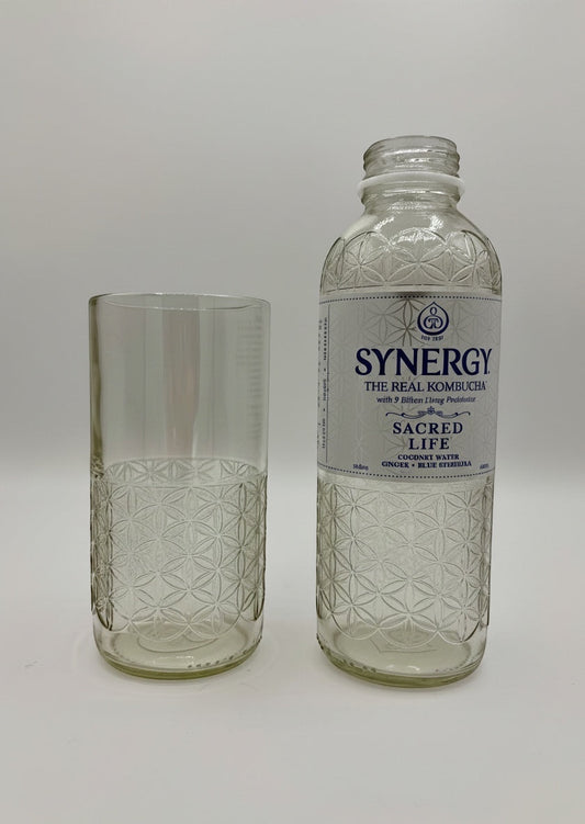 Broken Arrow Glass Recycling upcycled tumbler next to a Synergy kombucha bottle with embossed flower of life pattern
